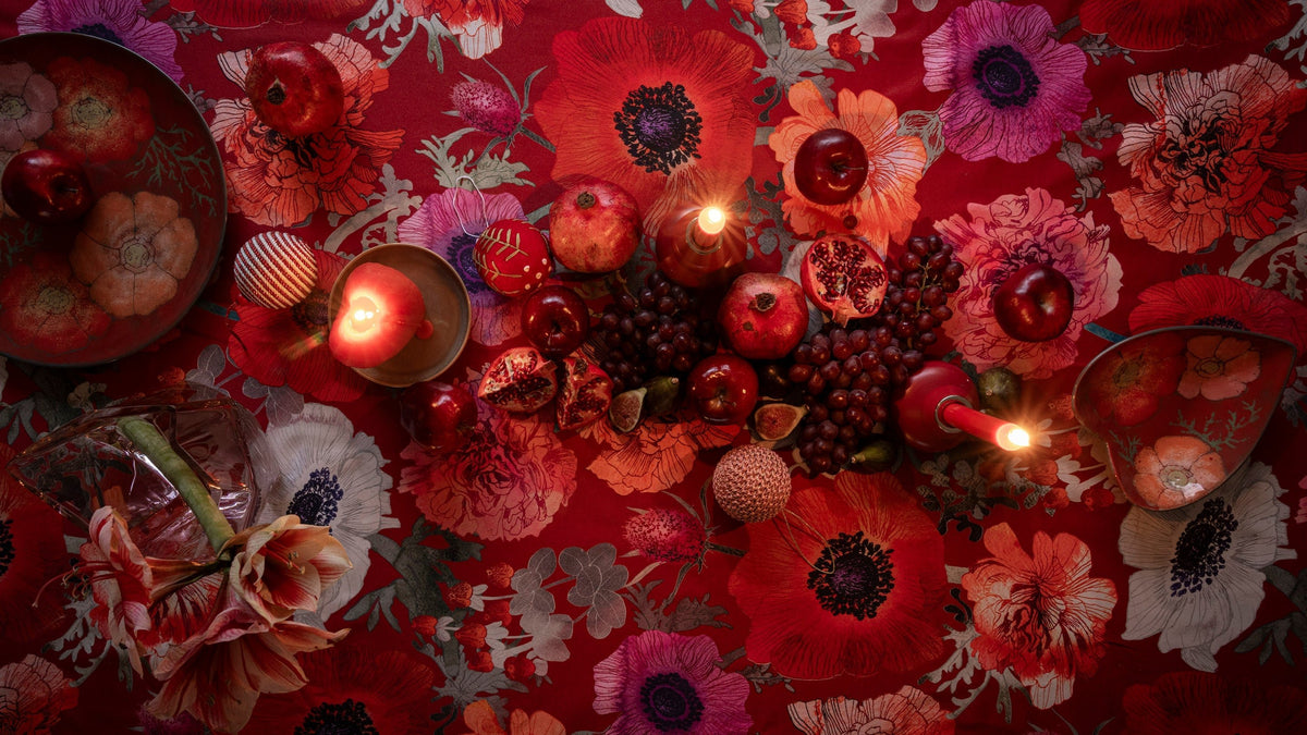On top of the Leinikki tablecloth, depicted directly from above, a light-coloured Kivi series plate and a wooden Lautta tray with apples.