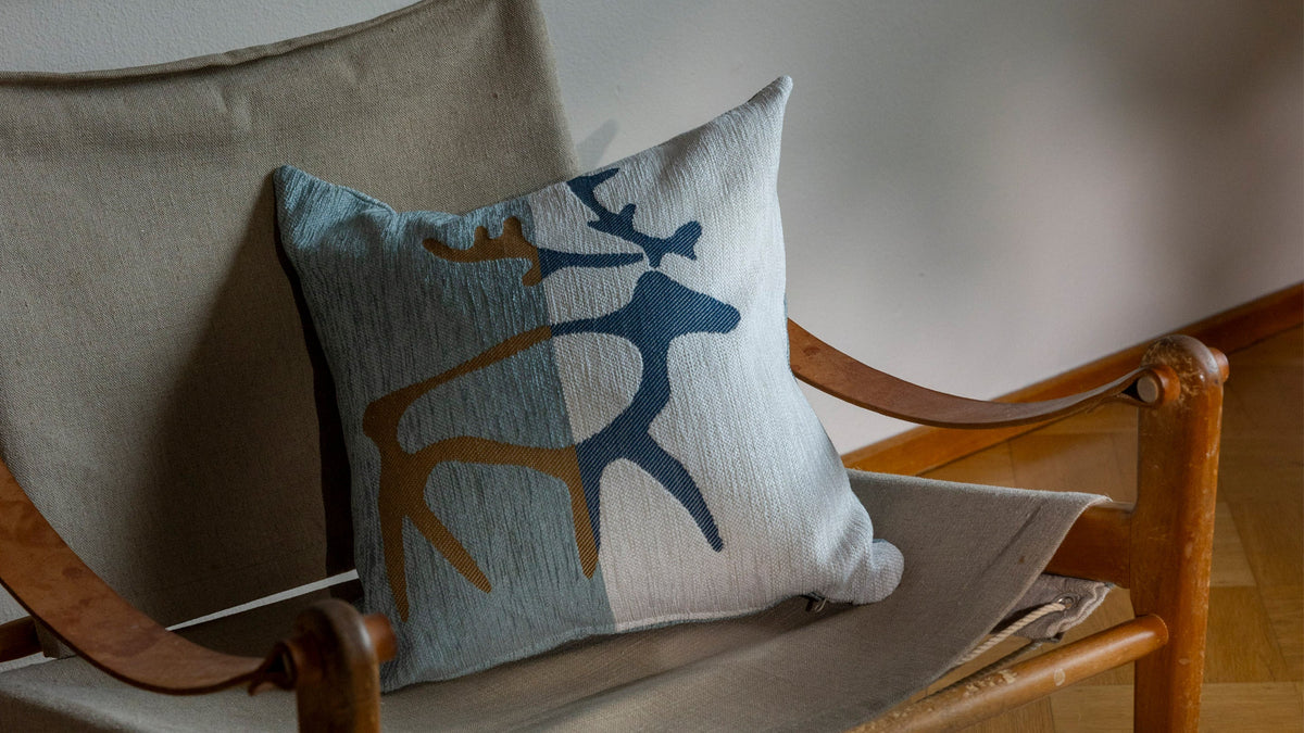 Three interior cushion covers stacked on top of a white wooden chair.