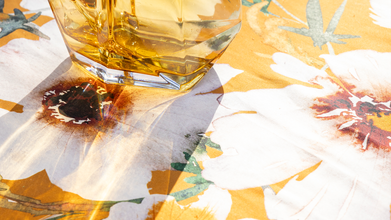 Close-up of a yellow floral fabric and a yellow glass vase reflecting light